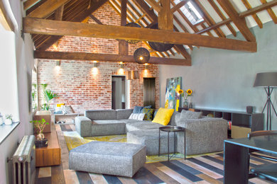 Inspiration for a large modern formal and grey and yellow open plan living room feature wall in Other with white walls, medium hardwood flooring, no fireplace, a wall mounted tv, exposed beams and brick walls.