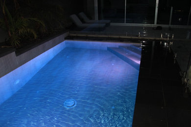 Réalisation d'une petite piscine minimaliste rectangle avec un point d'eau, une cour et des pavés en pierre naturelle.