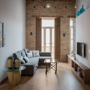 Mid-sized tuscan loft-style medium tone wood floor and exposed beam family room photo in Valencia with white walls and a wall-mounted tv
