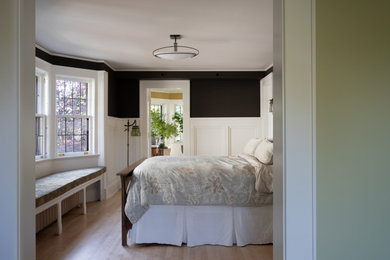Modelo de dormitorio principal de estilo americano grande con paredes marrones, suelo de madera clara, suelo marrón y boiserie