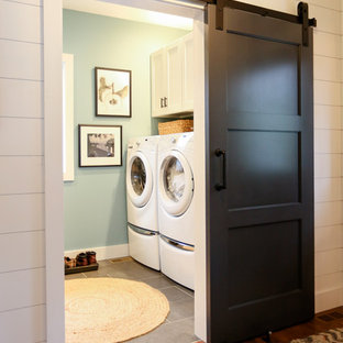 他の地域の中サイズのトランジショナルスタイルのおしゃれな家事室 (オープンシェルフ、白いキャビネット、木材カウンター、青い壁、磁器タイルの床、左右配置の洗濯機・乾燥機、グレーの床、茶色いキッチンカウンター) の写真