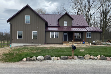 Mid-sized elegant brown two-story exterior home photo in Other with a metal roof