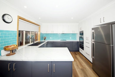 Design ideas for a mid-sized contemporary u-shaped kitchen in Other with a double-bowl sink, grey cabinets, quartz benchtops, blue splashback, subway tile splashback, black appliances, laminate floors, no island and white benchtop.