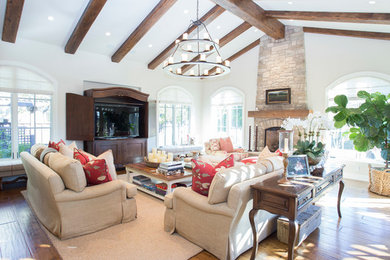 Inspiration for a large rustic medium tone wood floor and brown floor family room remodel in San Francisco with beige walls, a standard fireplace, a stone fireplace and a tv stand