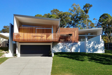 Photo of a mid-sized contemporary two-storey concrete white house exterior in Sunshine Coast with a flat roof and a metal roof.