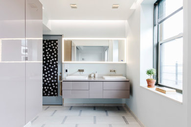 Trendy beige floor bathroom photo in New York with flat-panel cabinets, gray cabinets, white walls, a vessel sink and gray countertops