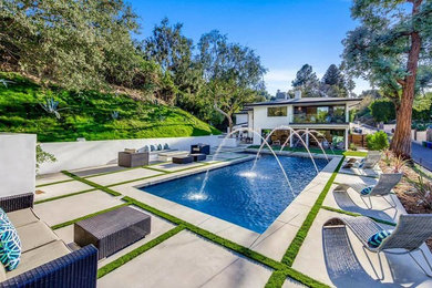 Inspiration for a large contemporary backyard rectangular lap pool in Los Angeles with a water feature and concrete pavers.