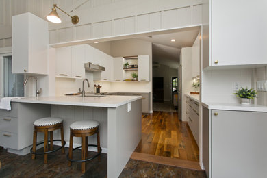 Eat-in kitchen - small contemporary u-shaped medium tone wood floor, brown floor and vaulted ceiling eat-in kitchen idea in Hawaii with a single-bowl sink, flat-panel cabinets, white cabinets, quartzite countertops, white backsplash, subway tile backsplash, stainless steel appliances and white countertops