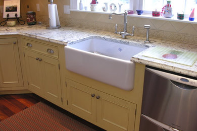 Large elegant u-shaped medium tone wood floor open concept kitchen photo in Portland Maine with a farmhouse sink, recessed-panel cabinets, yellow cabinets, granite countertops, beige backsplash, mosaic tile backsplash, stainless steel appliances and an island