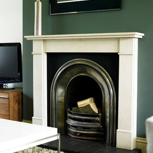 Foto på ett mellanstort funkis allrum med öppen planlösning, med heltäckningsmatta, en öppen vedspis, en spiselkrans i trä, en fristående TV och gröna väggar