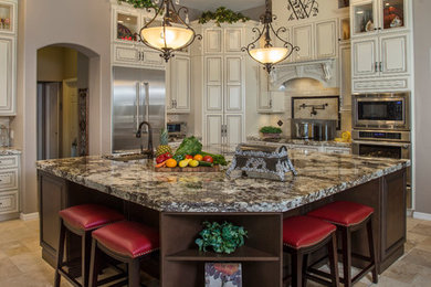 This is an example of a large traditional l-shaped open plan kitchen in Tampa with raised-panel cabinets, granite benchtops, stainless steel appliances and with island.