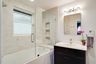 Bathroom - mid-sized transitional master white tile and marble tile porcelain tile, gray floor and single-sink bathroom idea in San Francisco with furniture-like cabinets, black cabinets, a one-piece toilet, white walls, an undermount sink, marble countertops, a hinged shower door, white countertops, a niche and a freestanding vanity
