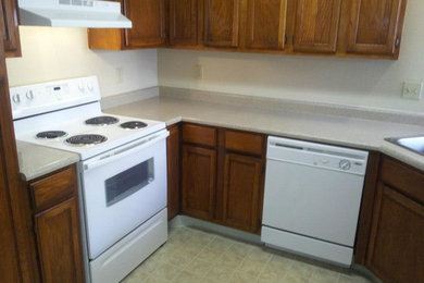 Enclosed kitchen - small traditional l-shaped ceramic tile and beige floor enclosed kitchen idea in Albuquerque with a double-bowl sink, white appliances, recessed-panel cabinets, medium tone wood cabinets, laminate countertops and no island