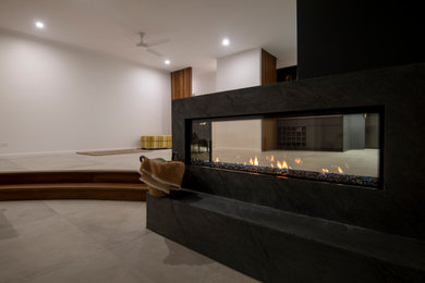 サンシャインコーストにある高級な中くらいなモダンスタイルのおしゃれなオープンリビング (両方向型暖炉、漆喰の暖炉まわり) の写真