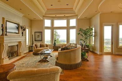Inspiration for a large transitional formal and open concept medium tone wood floor and brown floor living room remodel in Portland with beige walls, a standard fireplace, a plaster fireplace and a wall-mounted tv