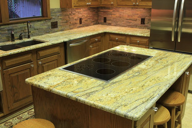 Inspiration for a mid-sized timeless l-shaped porcelain tile enclosed kitchen remodel in Austin with an undermount sink, raised-panel cabinets, medium tone wood cabinets, granite countertops, multicolored backsplash, stone tile backsplash, stainless steel appliances and an island
