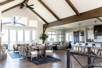 This is an example of a large country open concept living room in Salt Lake City with white walls, medium hardwood floors, a standard fireplace, a stone fireplace surround and a wall-mounted tv.