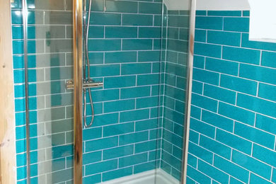 This is an example of a medium sized contemporary family bathroom with a freestanding bath, a corner shower, a wall mounted toilet, blue tiles, ceramic tiles, white walls and a wall-mounted sink.