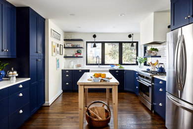 Inspiration for a mid-sized transitional u-shaped medium tone wood floor and brown floor eat-in kitchen remodel in DC Metro with a farmhouse sink, shaker cabinets, blue cabinets, quartz countertops, white backsplash, ceramic backsplash, stainless steel appliances, an island and white countertops