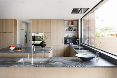 Eat-in kitchen - mid-sized contemporary l-shaped porcelain tile and gray floor eat-in kitchen idea in Phoenix with a single-bowl sink, flat-panel cabinets, light wood cabinets, quartzite countertops, paneled appliances and an island