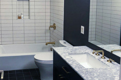 シアトルにあるお手頃価格の中くらいなおしゃれな浴室 (シェーカースタイル扉のキャビネット、青いキャビネット、シャワー付き浴槽	、セラミックタイル、磁器タイルの床、クオーツストーンの洗面台、黒い床、洗面台1つ、独立型洗面台) の写真