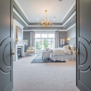 Photo of a large transitional master bedroom in Salt Lake City with grey walls, carpet, a standard fireplace and a wood fireplace surround.