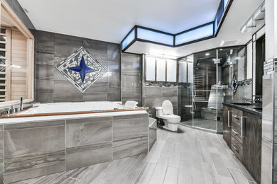 Inspiration for a huge contemporary master gray tile and porcelain tile laminate floor and gray floor bathroom remodel in Toronto with flat-panel cabinets, dark wood cabinets, a one-piece toilet, gray walls, an undermount sink, onyx countertops, a hinged shower door and black countertops