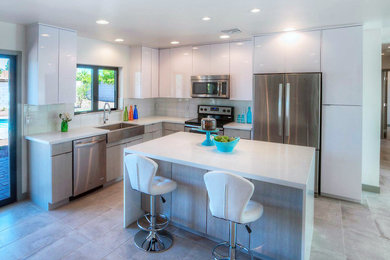 Open concept kitchen - mid-sized contemporary l-shaped open concept kitchen idea in Phoenix with a farmhouse sink, flat-panel cabinets, white cabinets, quartzite countertops, white backsplash, stainless steel appliances and an island
