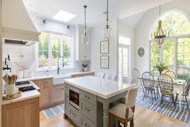 Example of a huge cottage u-shaped medium tone wood floor, brown floor and vaulted ceiling eat-in kitchen design in Philadelphia with a farmhouse sink, recessed-panel cabinets, light wood cabinets, quartzite countertops, white backsplash, stainless steel appliances, an island and white countertops