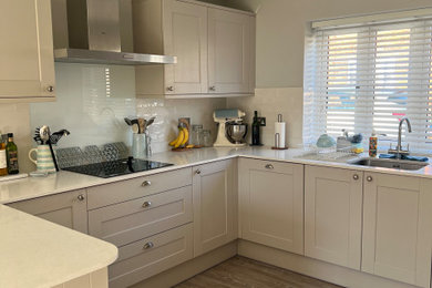 Medium sized classic u-shaped open plan kitchen in Dorset with shaker cabinets and a breakfast bar.