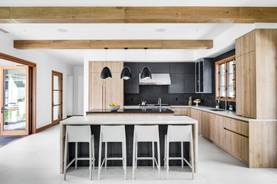 Inspiration for a mid-sized contemporary l-shaped cement tile floor and gray floor kitchen remodel in Orange County with an undermount sink, flat-panel cabinets, quartzite countertops, black backsplash, stone tile backsplash, paneled appliances, two islands, black cabinets and gray countertops