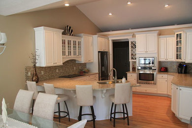 Eat-in kitchen - medium tone wood floor eat-in kitchen idea in New York with an undermount sink, white cabinets, quartz countertops, multicolored backsplash, mosaic tile backsplash, stainless steel appliances and a peninsula
