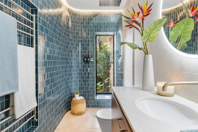Design ideas for a small contemporary master bathroom in Melbourne with flat-panel cabinets, medium wood cabinets, a curbless shower, a one-piece toilet, blue tile, ceramic tile, blue walls, porcelain floors, an undermount sink, engineered quartz benchtops, beige floor, an open shower, white benchtops, a single vanity and a floating vanity.