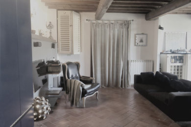フィレンツェにある高級な小さな地中海スタイルのおしゃれなLDK (ベージュの壁、テラコッタタイルの床、暖炉なし、壁掛け型テレビ、茶色い床、表し梁) の写真