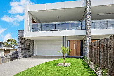 Photo of a mid-sized contemporary two-storey apartment exterior in Geelong with a flat roof and a metal roof.