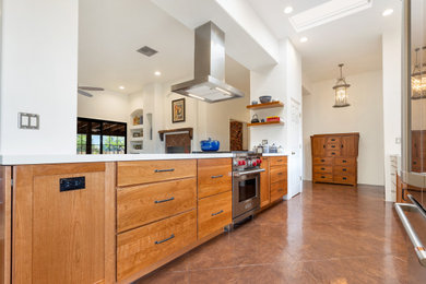 Eat-in kitchen - mid-sized southwestern galley concrete floor, brown floor and vaulted ceiling eat-in kitchen idea in Other with a farmhouse sink, flat-panel cabinets, brown cabinets, quartz countertops, yellow backsplash, ceramic backsplash, stainless steel appliances, an island and white countertops