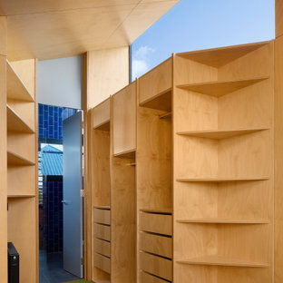 Immagine di un armadio incassato minimal di medie dimensioni con ante lisce, ante in legno chiaro, moquette, pavimento verde e soffitto in legno