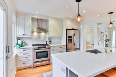 Example of a mid-sized transitional galley porcelain tile and multicolored floor eat-in kitchen design in New York with a drop-in sink, white cabinets, quartzite countertops, gray backsplash, ceramic backsplash, stainless steel appliances, an island and white countertops