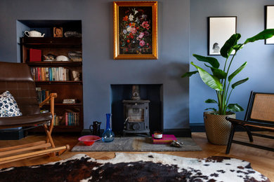 Ejemplo de salón abierto bohemio de tamaño medio con paredes azules y estufa de leña