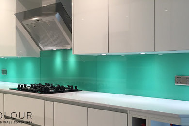 Design ideas for a large contemporary u-shaped enclosed kitchen in Cornwall with flat-panel cabinets, white cabinets, composite countertops, green splashback, glass tiled splashback, no island and white worktops.