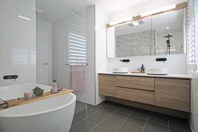 Photo of a mid-sized modern kids bathroom in Brisbane with shaker cabinets, light wood cabinets, a freestanding tub, an alcove shower, a two-piece toilet, white tile, ceramic tile, white walls, porcelain floors, a vessel sink, engineered quartz benchtops, grey floor, an open shower and white benchtops.