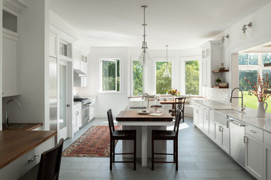 Inspiration for a large transitional u-shaped porcelain tile kitchen pantry remodel in Burlington with a farmhouse sink, recessed-panel cabinets, white cabinets, quartzite countertops, white backsplash, ceramic backsplash, stainless steel appliances, an island and white countertops