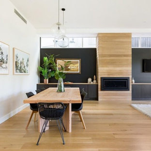 Modernes Esszimmer mit schwarzer Wandfarbe, hellem Holzboden, Gaskamin, Kaminsims aus Holz und braunem Boden in Sydney