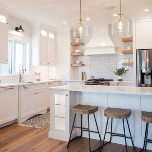 Mid-sized transitional kitchen pantry ideas - Example of a mid-sized transitional l-shaped medium tone wood floor and brown floor kitchen pantry design in Edmonton with a drop-in sink, shaker cabinets, white cabinets, quartzite countertops, white backsplash, subway tile backsplash, stainless steel appliances, an island and white countertops