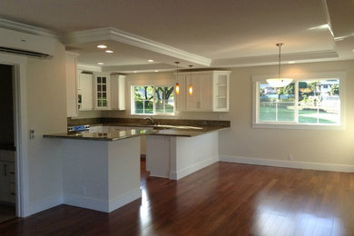 Large l-shaped medium tone wood floor kitchen photo in Hawaii with a double-bowl sink, glass-front cabinets, white cabinets, granite countertops, stainless steel appliances and an island