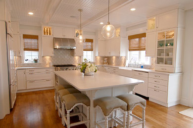Photo of a traditional u-shaped eat-in kitchen in New York with a farmhouse sink, recessed-panel cabinets, white cabinets, beige splashback, panelled appliances, medium hardwood floors and with island.