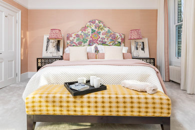 ロンドンにある広いエクレクティックスタイルのおしゃれな主寝室 (ピンクの壁、カーペット敷き、標準型暖炉、木材の暖炉まわり、グレーの床、壁紙)