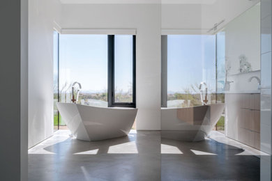 Foto de cuarto de baño principal moderno grande con bañera exenta y suelo de cemento
