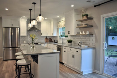Open concept kitchen - mid-sized traditional u-shaped laminate floor and brown floor open concept kitchen idea in Charlotte with shaker cabinets, white cabinets, an island, an undermount sink, granite countertops, white backsplash, subway tile backsplash, stainless steel appliances and gray countertops