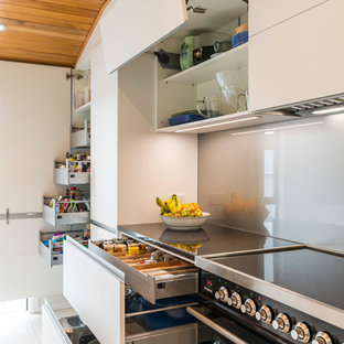 Mid-sized contemporary kitchen pantry photos - Kitchen pantry - mid-sized contemporary galley ceramic floor and white floor kitchen pantry idea in Christchurch with an undermount sink, flat-panel cabinets, white cabinets, quartz countertops, gray backsplash, glass sheet backsplash, stainless steel appliances and an island